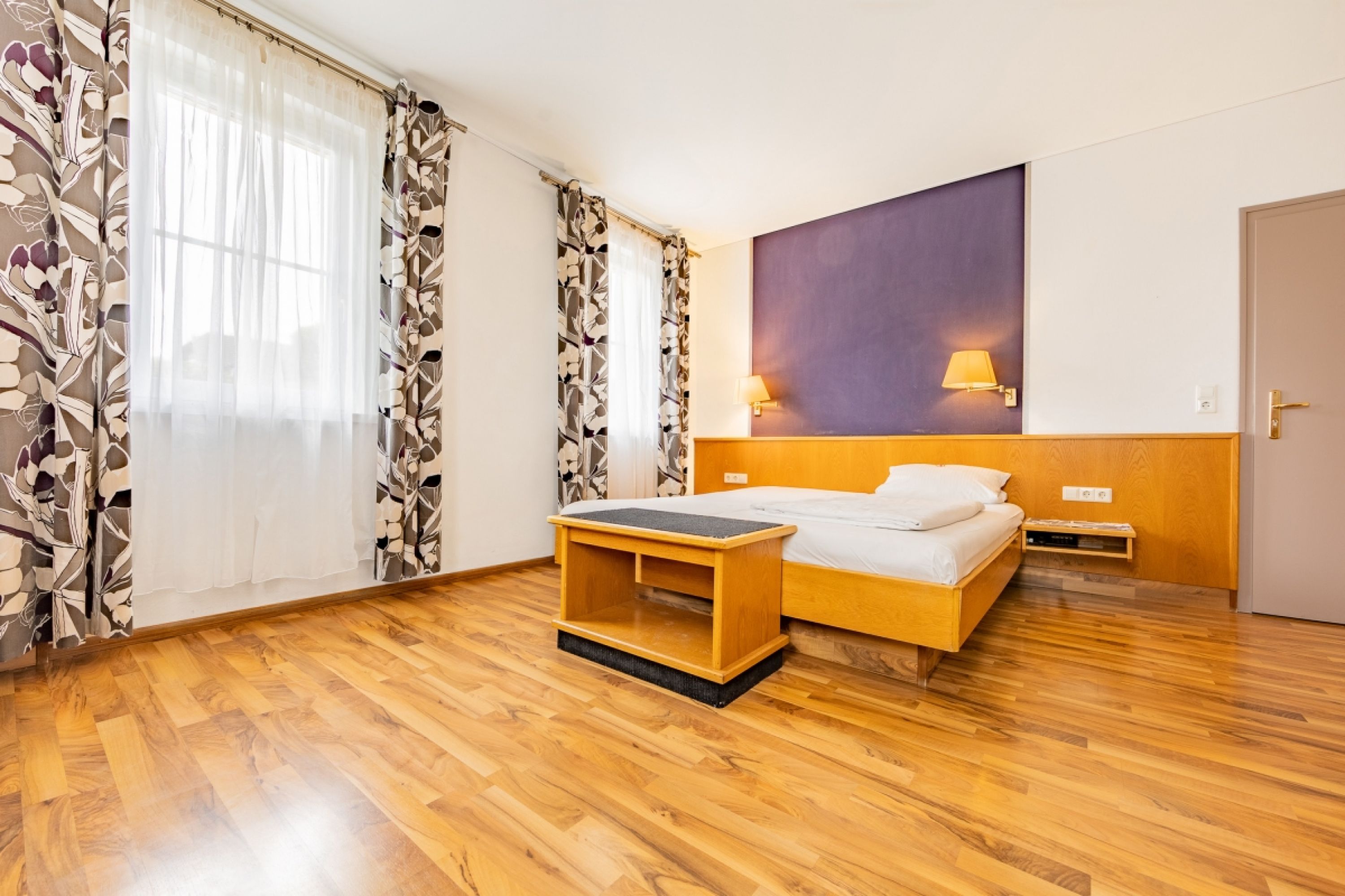 Zimmer mit Bett und 2 Fenstern